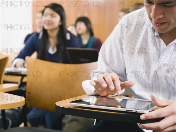 College students taking notes in lecture hall.