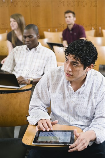 College students taking notes in lecture hall.