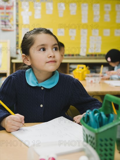 Kindergarten student writing in notebook.