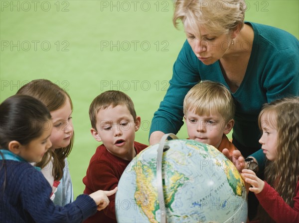 Teacher showing globe to kindergarten students.