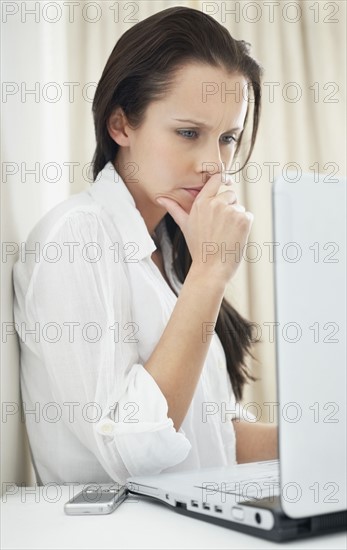 Confused woman looking at laptop. Photo : momentimages