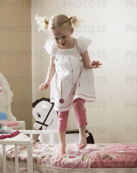 Young girl dancing on her bed. Photo : Mike Kemp