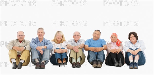 A group of people sitting on the floor in a row. Photo : momentimages