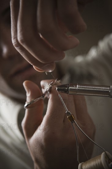 Man repairing fly fishing hook. Photo : Mike Kemp