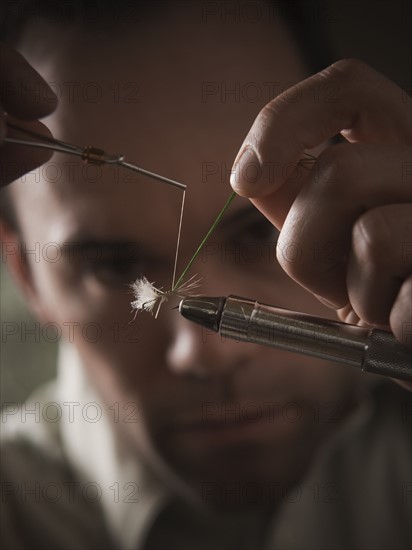 Man repairing fly fishing hook. Photo : Mike Kemp