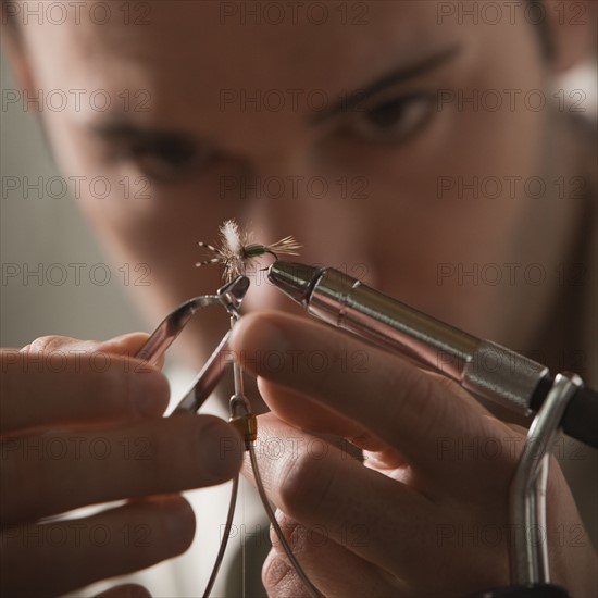 Man repairing fly fishing hook. Photo : Mike Kemp