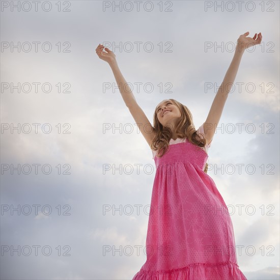 Teenage girl raising her arms in the air. Photo : Mike Kemp