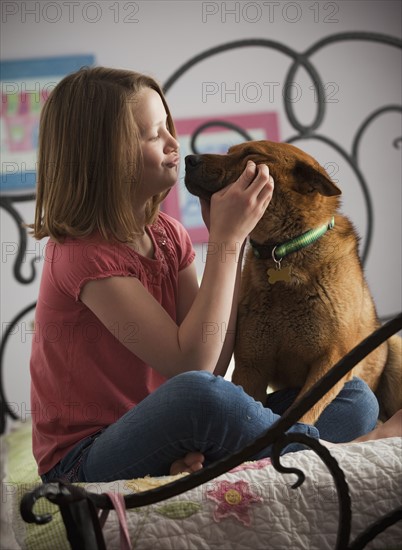 Young girl playing with dog on bed. Photo : Mike Kemp