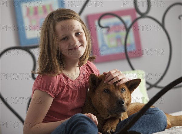 Young girl relaxing with dog on bed. Photo : Mike Kemp