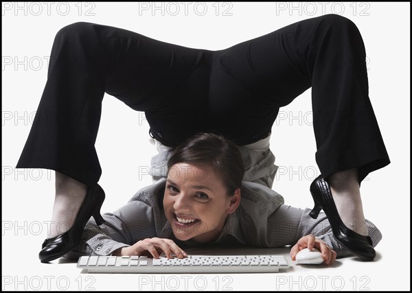 Businesswoman contorting her body while typing. Photo : Mike Kemp