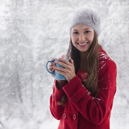 Woman in the snow holding a warm drink. Photo : Mike Kemp