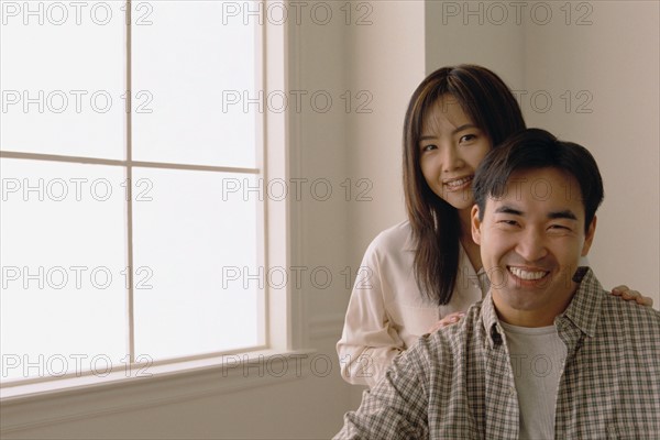 Happy couple standing by the window in their home. Photo : Rob Lewine