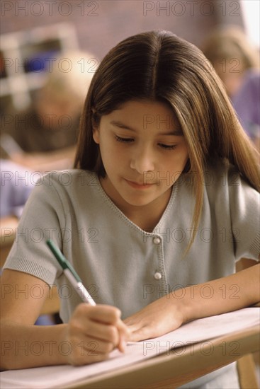 Elementary school student writing at her desk. Photo : Rob Lewine