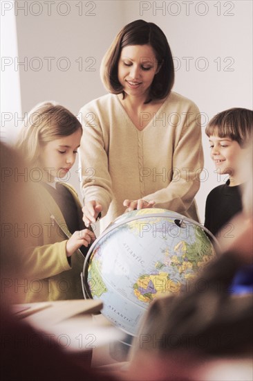 Elementary school teacher showing globe to students. Photo : Rob Lewine