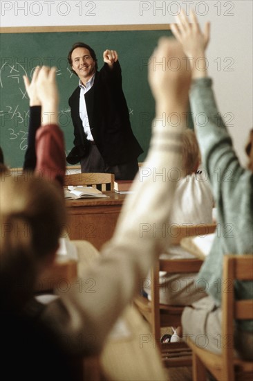 Students raising their hands in classroom. Photo : Rob Lewine