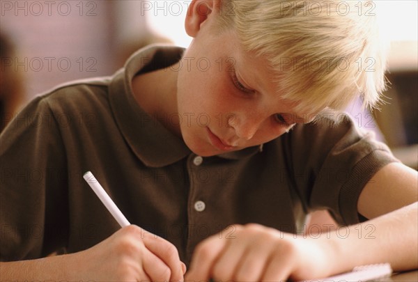 Elementary school student writing at his desk. Photo : Rob Lewine