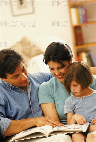 Parents and their young daughter reading together. Photo : Rob Lewine