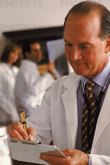 Doctor writing on his clipboard. Photo : Rob Lewine