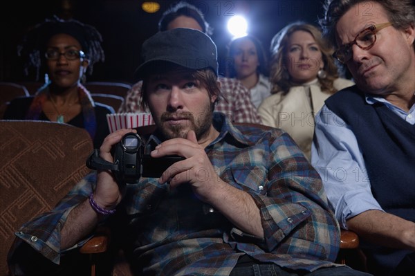 Man using video recorder in movie theatre. Photo : Dan Bannister