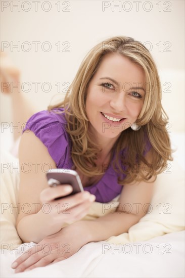 Relaxed woman holding cell phone. Photo : Dan Bannister