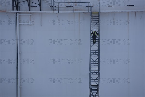 Worker walking down stairs on an oil tank. Photo : Dan Bannister
