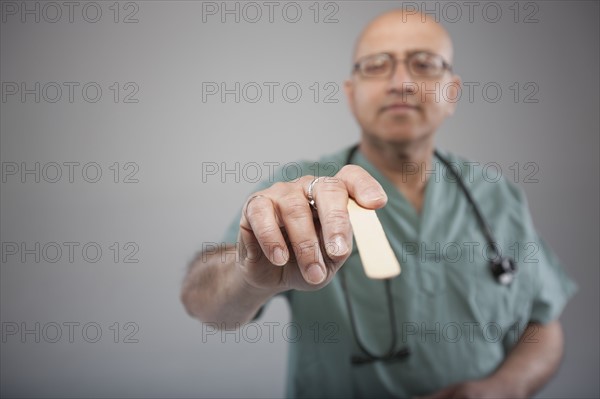 Doctor holding a tongue depressor. Photo : Dan Bannister