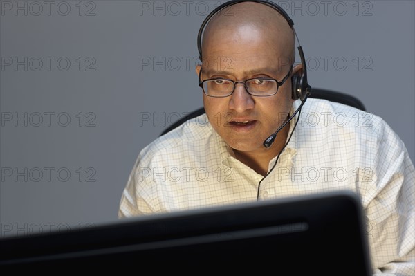 Man wearing headset working on computer. Photo : Dan Bannister