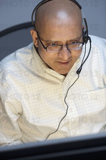 Man wearing headset working on computer. Photo : Dan Bannister