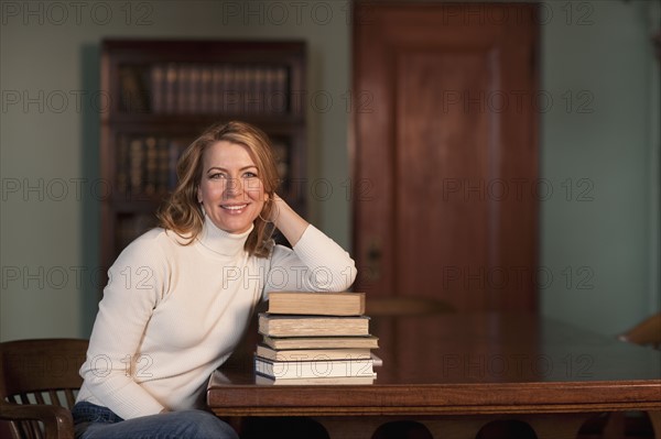 Woman leaning on stack of books. Photo : Dan Bannister