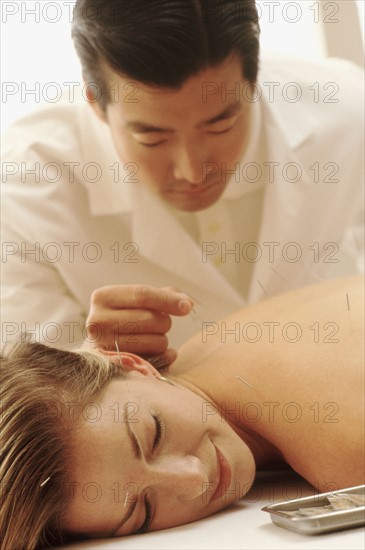 Acupuncturist putting needles in woman's back. Photo : Rob Lewine