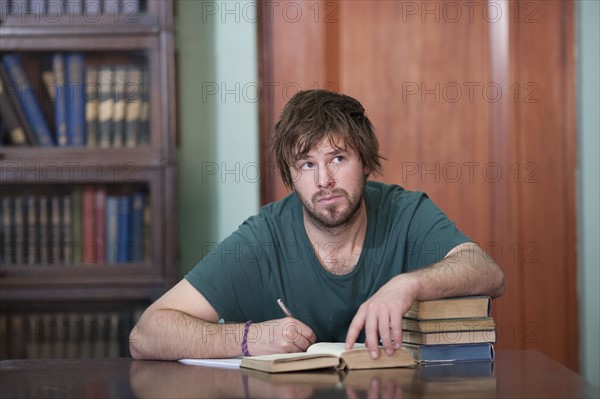 Man in library taking notes. Photo : Dan Bannister