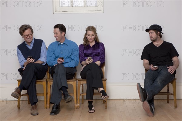 People sitting in row while holding cell phones. Photo : Dan Bannister