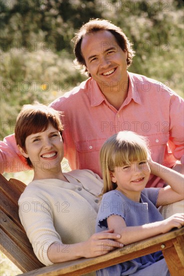 Parents and their young daughter sitting in Adirondack chair. Photo : Rob Lewine