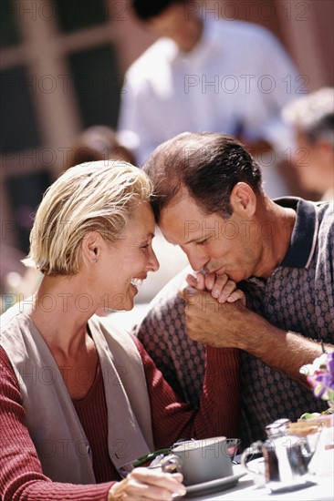 Man kissing woman's hand while sitting at patio table. Photo : Rob Lewine