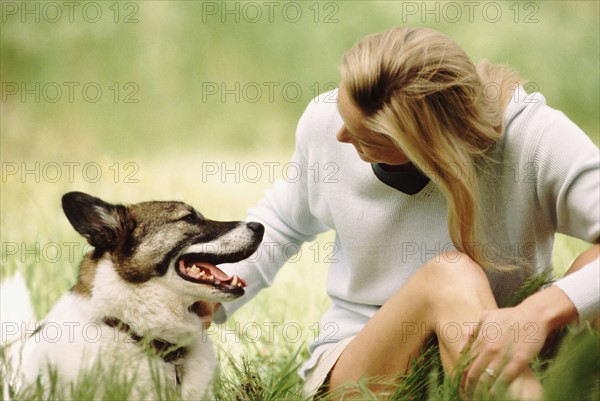 Woman sitting in meadow with dog. Photo : Rob Lewine