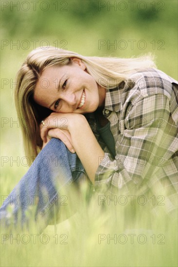 Pretty woman relaxing on grass in meadow. Photo : Rob Lewine