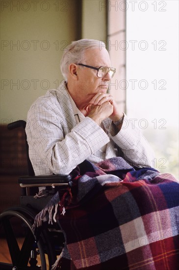 Elderly man sitting in wheelchair while gazing out window. Photo : Rob Lewine