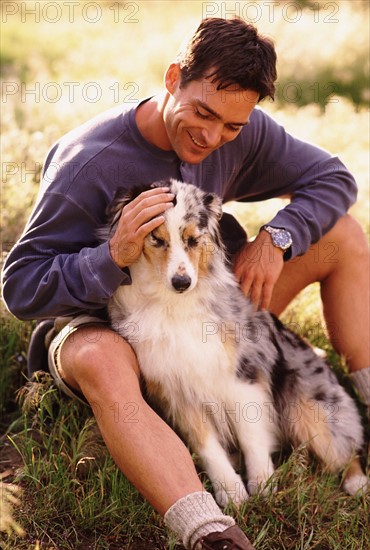 Man and his dog sitting on grass. Photo : Rob Lewine