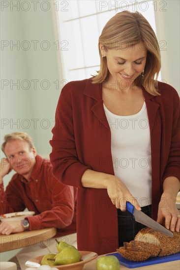 Woman slicing bread and her husband watches. Photo : Rob Lewine