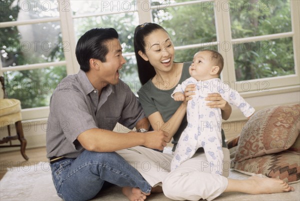 Happy parents sitting with their infant son. Photo : Rob Lewine