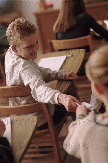 Students passing a note in classroom. Photo : Rob Lewine