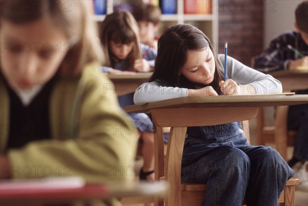 Elementary school students writing at their desk. Photo : Rob Lewine