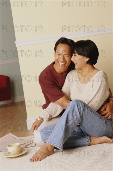 Happy couple sitting together on the floor in their home. Photo : Rob Lewine