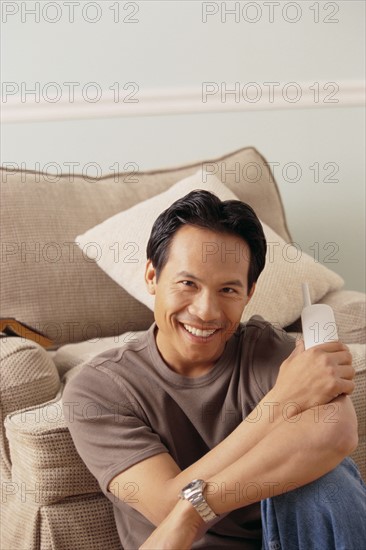 Smiling man sitting on floor in living room. Photo : Rob Lewine