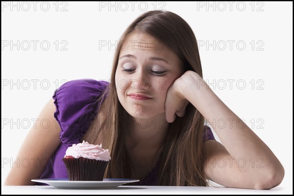 Woman with a sweet tooth resisting a cupcake. Photo : Mike Kemp