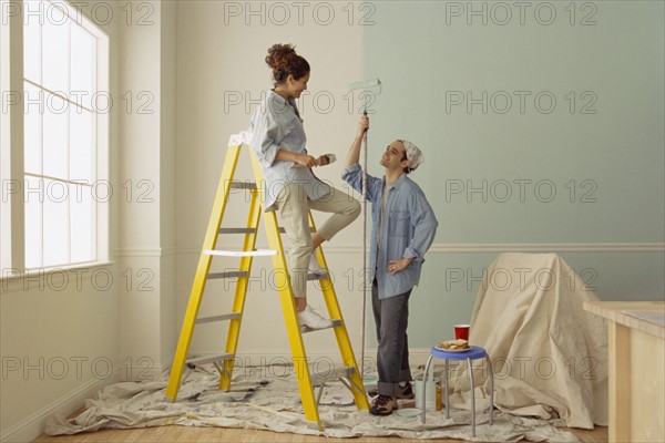 Happy couple painting the walls in their home. Photo : Rob Lewine