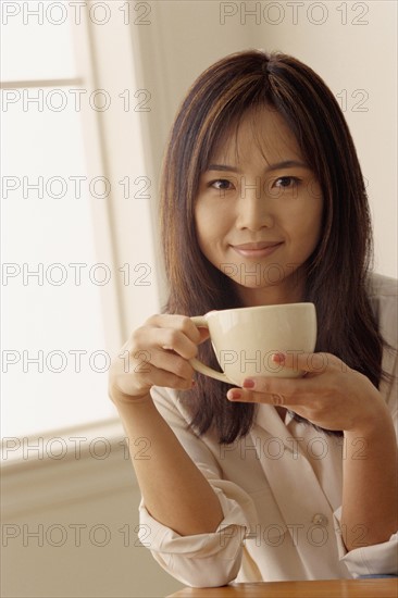 Attractive woman holding a cup of coffee. Photo : Rob Lewine