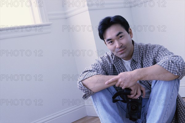 Relaxed man sitting on the floor in his home. Photo : Rob Lewine