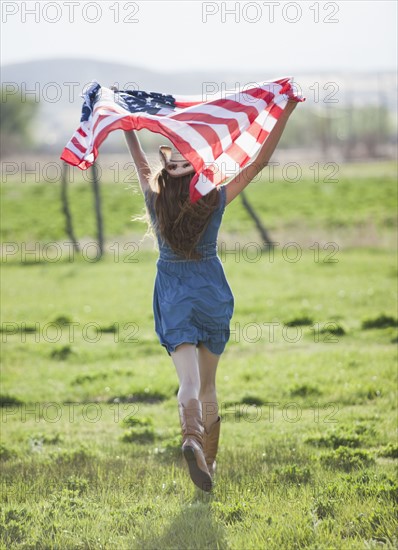 Beautiful cowgirl running with American flag in her arms. Photo : Mike Kemp