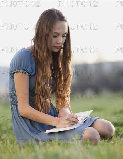 Beautiful long haired woman writing in journal. Photo : Mike Kemp